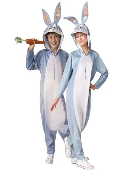 Two children wearing matching blue and white bunny onesies with attached hoods featuring bunny ears, one holding a large plush carrot, both smiling and posing playfully.