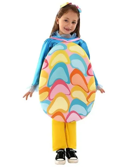 Young girl wearing a colourful Easter egg costume featuring a bright, patterned egg-shaped tunic over a blue top and yellow pants, smiling with arms outstretched.